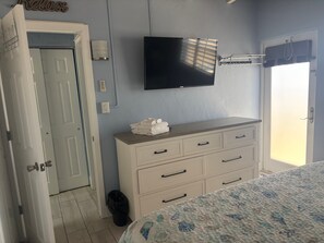 Une chambre à coucher avec un lit, une commode, un téléviseur et une porte.