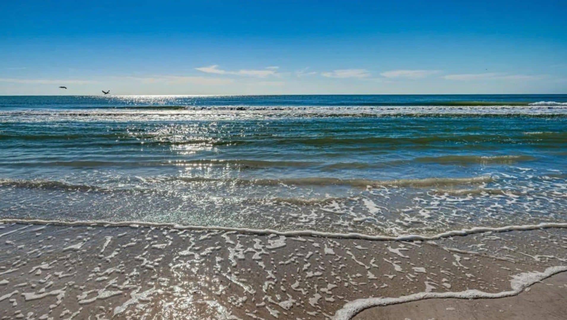 A beach with waves and a clear sky.