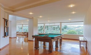 A spacious room with a pool table, large windows, and a view of greenery. - 2-bedroom Apt in Campos do Jordao Lvr0412 (Campos do Jordão)