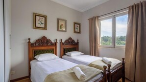 A hotel room with two beds, a large window with curtains, and three framed floral pictures on the wall. - 2-bedroom Apt in Campos do Jordao Lvr0412 (Campos do Jordão)