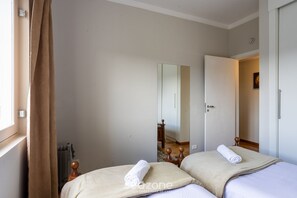 A bedroom with two beds, a radiator, a wooden headboard, and a window with curtains. - 2-bedroom Apt in Campos do Jordao Lvr0412 (Campos do Jordão)