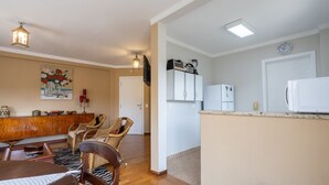 A dining area with wicker chairs, a wooden table, and a painting on the wall. - 2-bedroom Apt in Campos do Jordao Lvr0412 (Campos do Jordão)