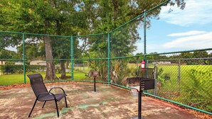A fenced outdoor area with a bench and a trash receptacle. - Pool & Palm Escape – Unit C208 (Biloxi)
