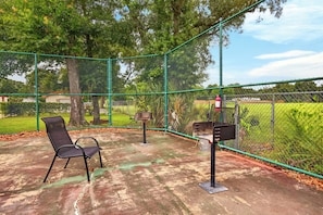 A fenced outdoor area with a bench and a trash receptacle. - Pool & Palm Escape – Unit C208 (Biloxi)