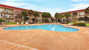 A hotel with a swimming pool, multiple balconies, and palm trees. - Pool & Palm Escape – Unit C208 (Biloxi)