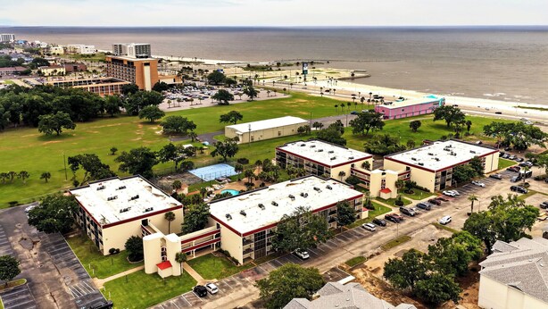 A coastal hotel with multiple buildings, parking areas, and a view of the ocean. - Pool & Palm Escape – Unit C208 (Biloxi)