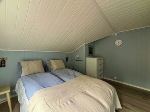 A bedroom with a bed, a dresser, a clock, and a wall-mounted light fixture.