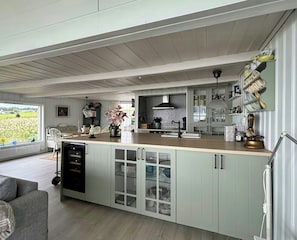 A spacious kitchen with a large island, open shelving, and a view of the outdoors.