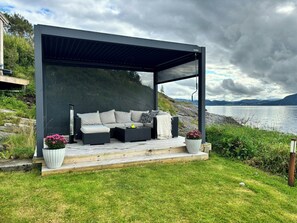 A modern outdoor seating area with a sofa and cushions, a small table, and potted plants.