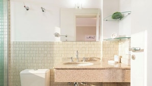 A bathroom with a white toilet, a sink with a granite countertop, a mirror, and a shower with a glass enclosure. - Apt in Condo w/ BBQ in Capivari Lvr0017 (Campos do Jordão)