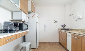 Una cocina compacta equipada con cafetera, microondas y refrigerador.