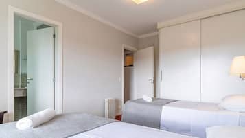 Une chambre d’hôtel avec deux lits, une salle de bain visible à travers une porte ouverte et un radiateur.