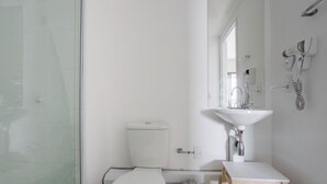 Ein modernes Badezimmer mit einer Duschkabine aus Glas, einer weißen Toilette und einem Waschbecken mit Spiegel darüber.