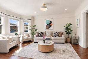 A spacious living room with a round coffee table, two sofas, and a large window providing a view of the city.