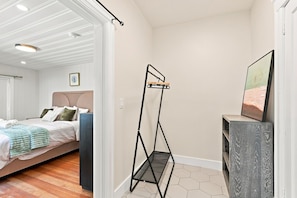 A bedroom with a bed, a bedside table, a wall-mounted TV, and a black metal drying rack.