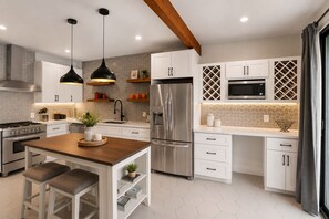 A modern kitchen with a central island, stainless steel appliances, and pendant lighting.