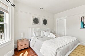 A bedroom with a bed, bedside table, lamp, and artwork on the walls. - Restored Lake Merritt Victorian Retreat (Oakland)