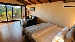 A bedroom with a large bed, a bedside lamp, and a view of the outdoors through a sliding door.