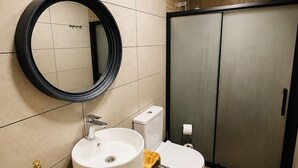 A modern bathroom with a round mirror, a sink, and a toilet.