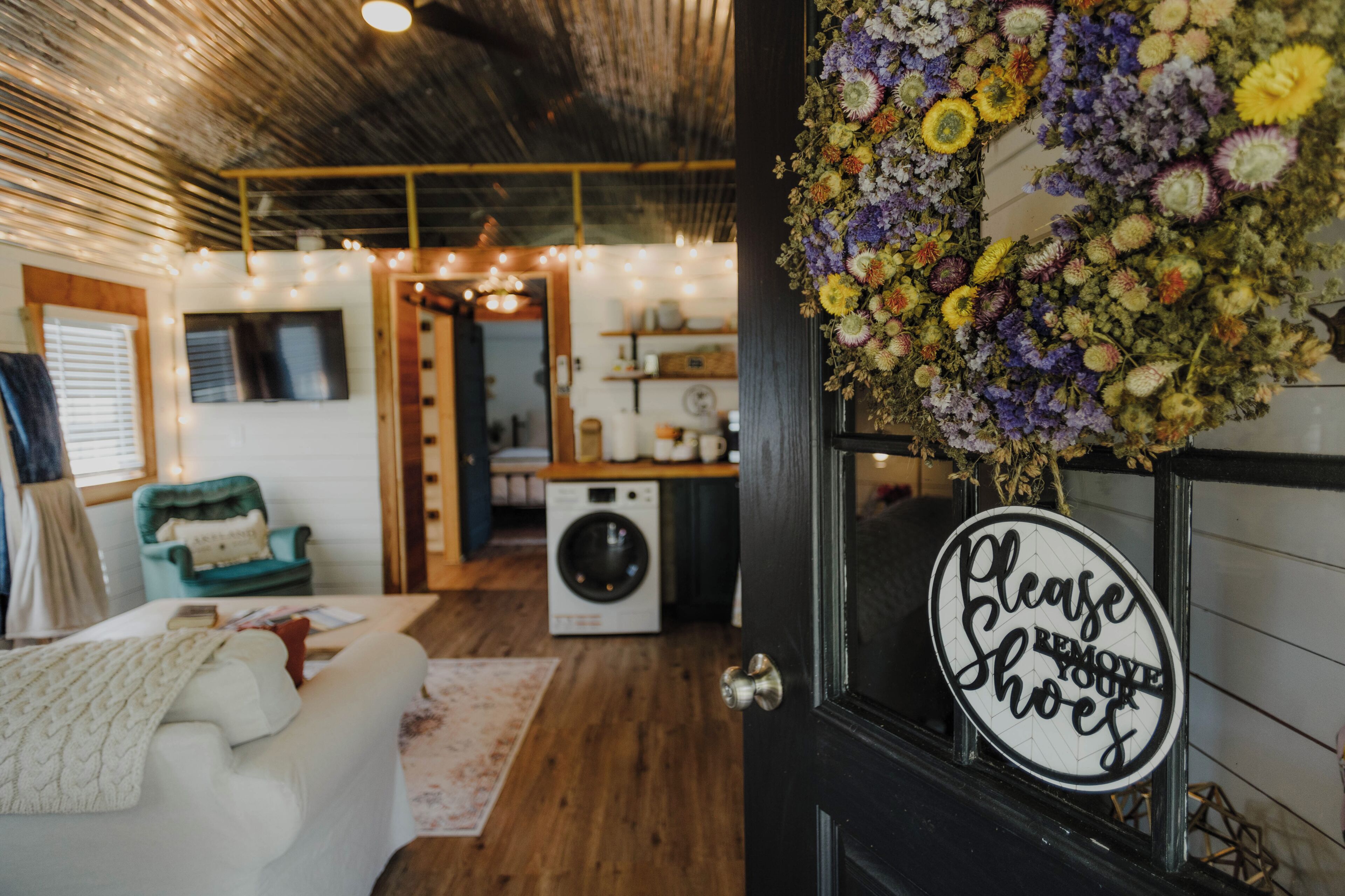 A cozy room with a washing machine, a sofa, and a floral arrangement on a door.