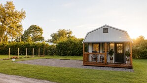 Une petite maison de plain-pied avec un porche, entourée d’une pelouse bien entretenue et d’un chemin de gravier menant à l’entrée.