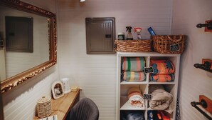 Une salle de bain avec un miroir, une étagère avec des serviettes et un meuble de rangement.