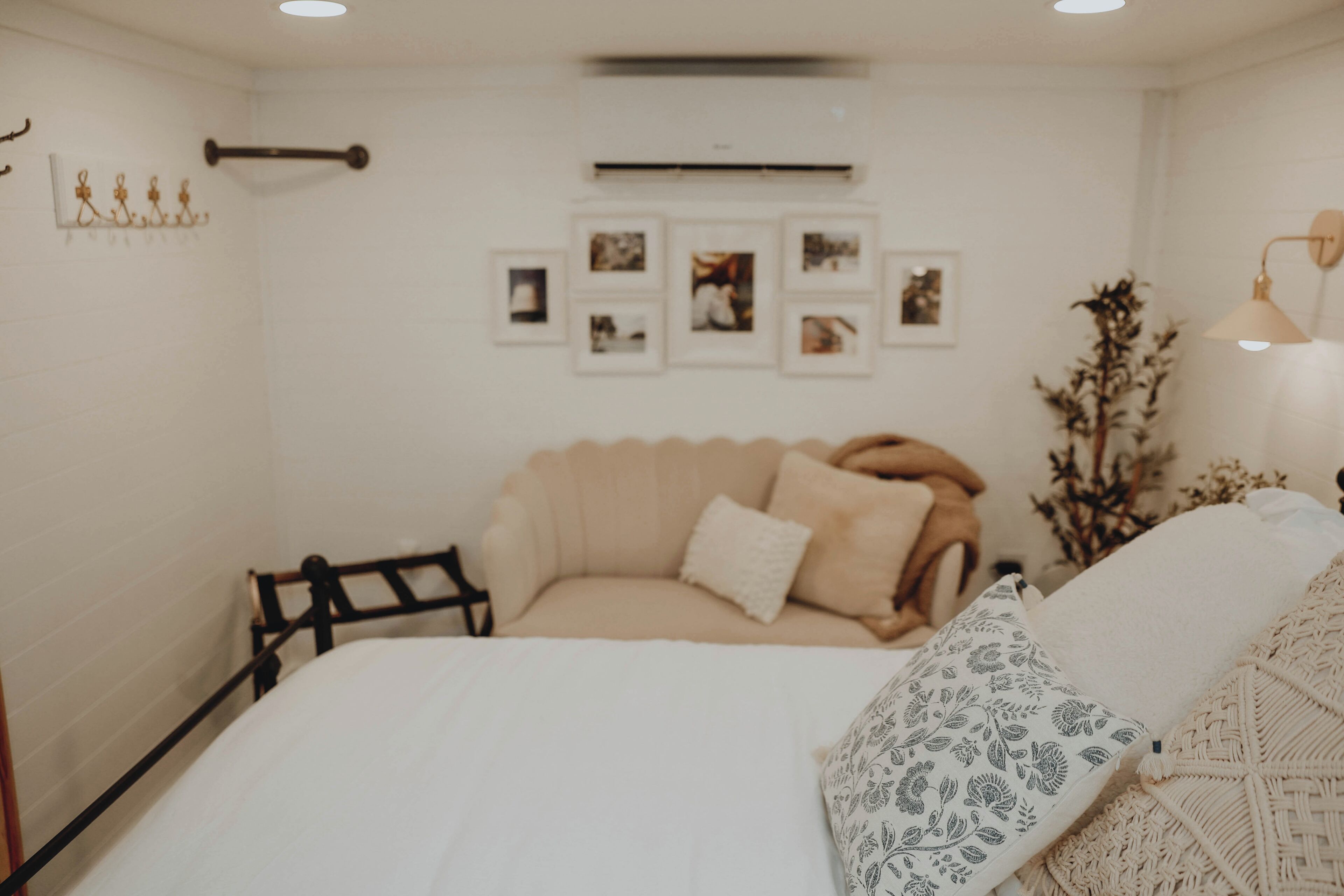 A bedroom with a bed, a bedside table, a lamp, and wall-mounted pictures.
