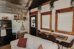 Un intérieur chaleureux avec un canapé blanc, une table à manger en bois et un réfrigérateur noir.