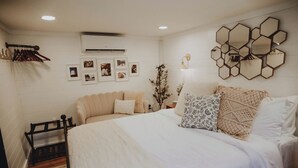Une chambre à coucher comprenant un lit, une table de chevet, un climatiseur fixé au mur et un mur orné de miroirs hexagonaux.