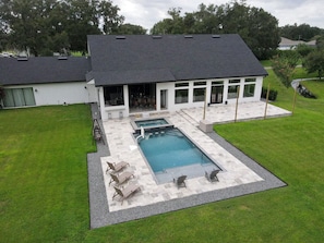 A modern house with a swimming pool, outdoor seating, and a covered patio area.