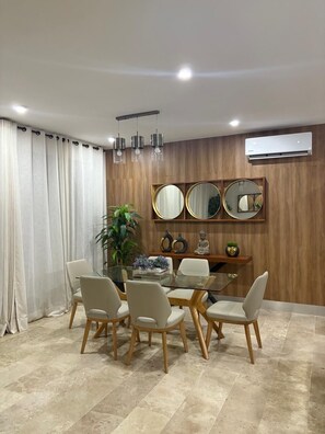 Un comedor con una mesa redonda, sillas y un espejo en la pared.