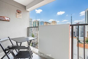 A balcony with a table and chairs, a sign with 'PORTA ESPETO' and 'Churrasco', and a view of city buildings. - Modern Studio 250m From Paulista Metro Nxo2104 (São Paulo)