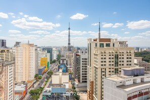 A high-rise building with a prominent antenna, surrounded by other tall buildings and a busy street. - Modern Studio 250m From Paulista Metro Nxo2104 (São Paulo)