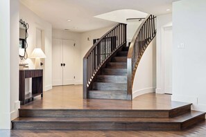 A staircase with wooden steps and a dark metal railing, leading to a landing with a white door.
