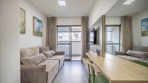 A modern hotel room with a sofa set, a long table, a flat-screen TV, and a large window with curtains. - Full Apt 250m From Paulista Metro Station Nxo1402 (São Paulo)