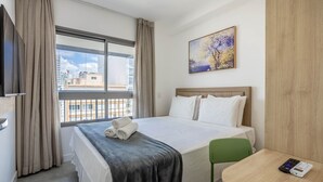 A hotel room with a bed, a painting, a window with curtains, and a view of buildings. - Full Apt 250m From Paulista Metro Station Nxo1402 (São Paulo)
