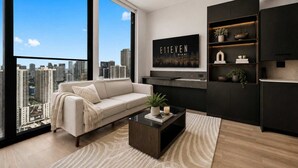 A modern living room with a sofa, coffee table, and a city view through large windows. - Luxury E11EVEN 35th Floor Suite w/ City & Bay View (Miami)
