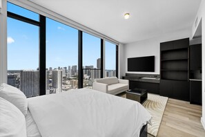 A modern bedroom with a large bed, a seating area, a TV, and a city view. - Luxury E11EVEN 35th Floor Suite w/ City & Bay View (Miami)