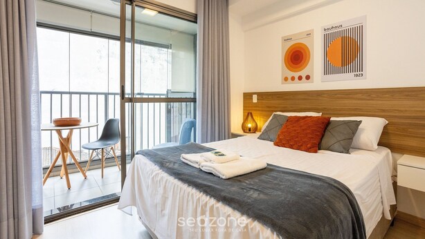 A modern hotel room with a large bed, a wooden headboard, and a balcony with a view. - Modern Apartment 250m From Paulista Metro Nxo0404 (São Paulo)