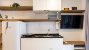 A compact kitchen with white cabinets, a built-in microwave, a sink, and a small countertop. - Modern Apartment 250m From Paulista Metro Nxo0404 (São Paulo)