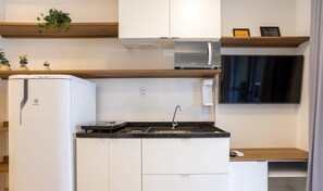 A compact kitchen with white cabinets, a built-in microwave, a sink, and a small countertop. - Modern Apartment 250m From Paulista Metro Nxo0404 (São Paulo)