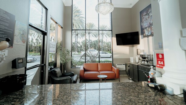A hotel lobby with a large window, a sofa, a coffee machine, and a television. - Family Suite 1 Queen Room (Anaheim)