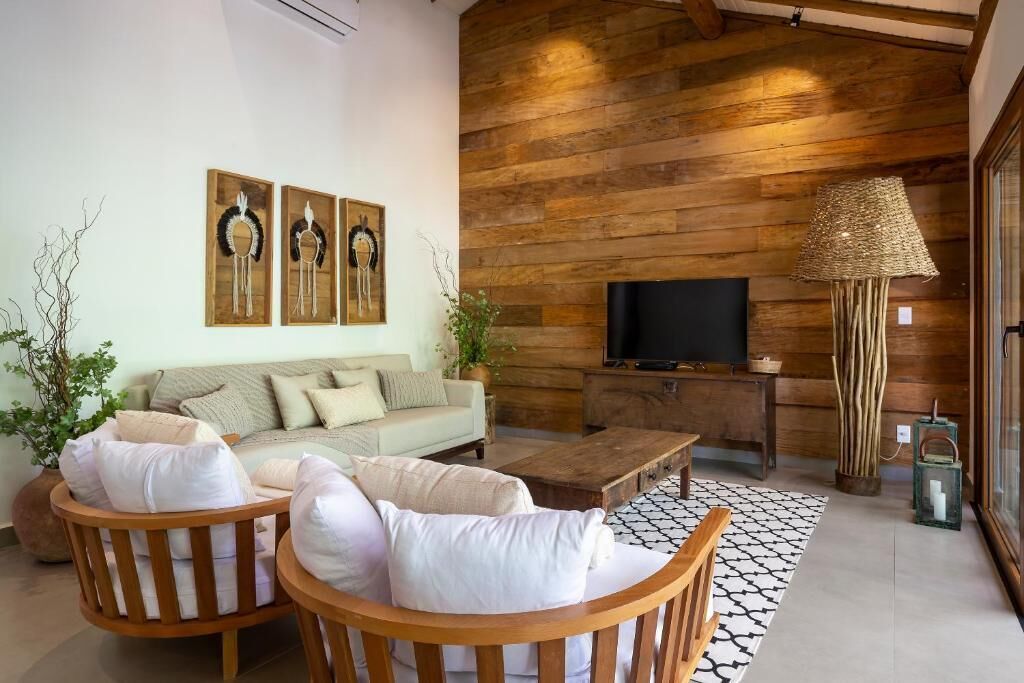 A modern living room with a sofa, two wooden chairs, a coffee table, a TV, and a woven lamp.