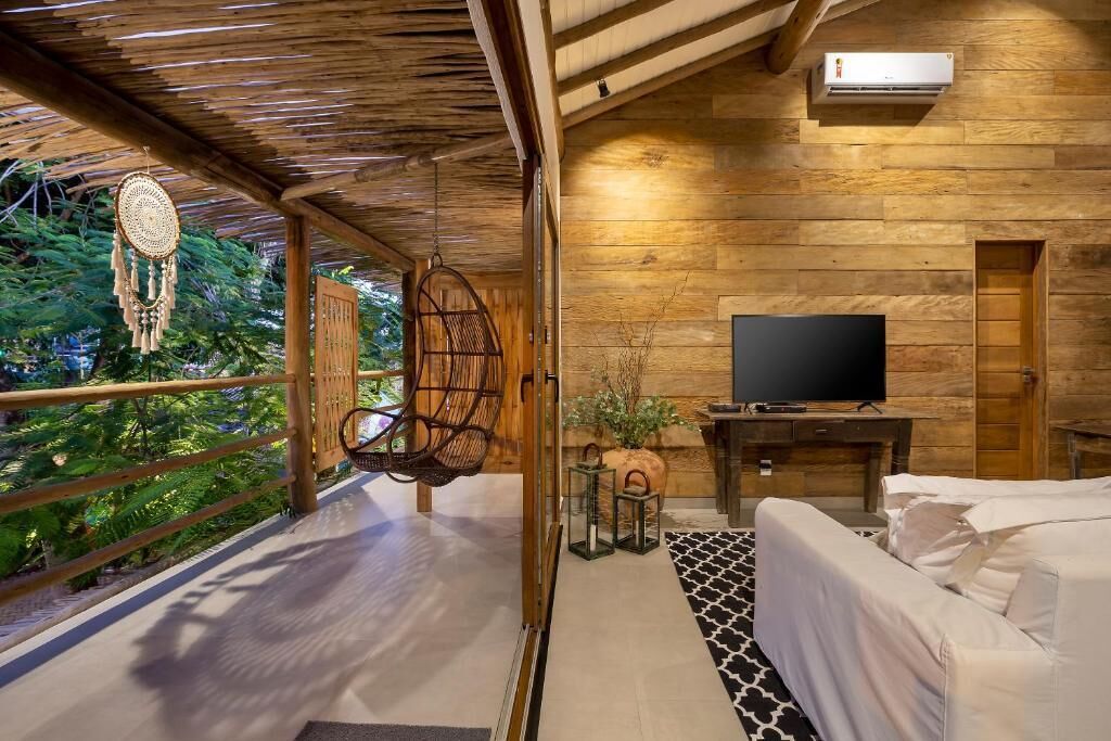 Un interior de madera con una cama, un televisor y una silla colgante.