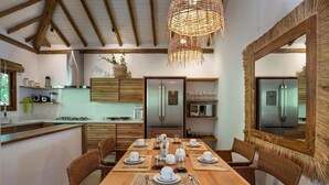 A dining area with a wooden table set for six, surrounded by wicker chairs, and a large mirror on the wall. - Flamboyant Residence Quadrado (Porto Seguro)