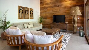 A living room with a sofa, two wooden chairs, a coffee table, a TV, and a lamp. - Flamboyant Residence Quadrado (Porto Seguro)