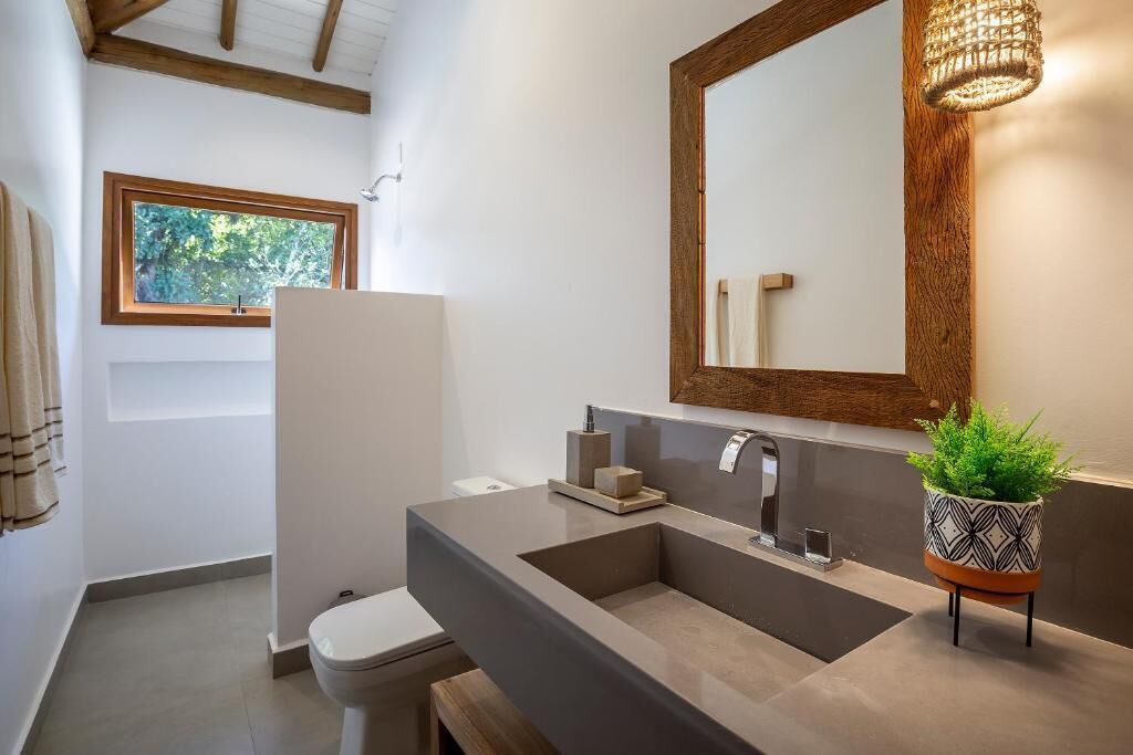 A modern bathroom with a large mirror, a built-in sink, and a window.