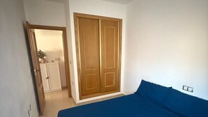 Ein Schlafzimmer mit einem Bett, einem Deckenventilator, einem Kleiderschrank und einer Tür zu einem Badezimmer.