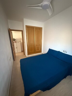Ein Schlafzimmer mit einem Bett, einem Deckenventilator, einem Kleiderschrank und einer Tür zu einem Badezimmer.