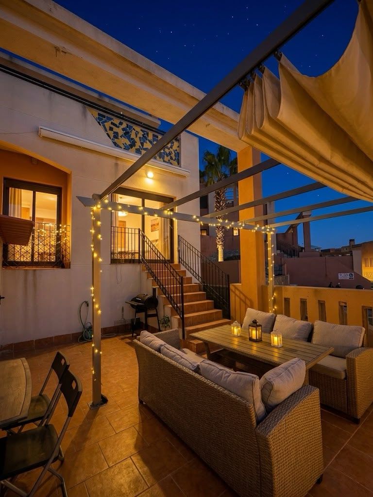 An outdoor patio area with a sofa set, a table, and string lights.